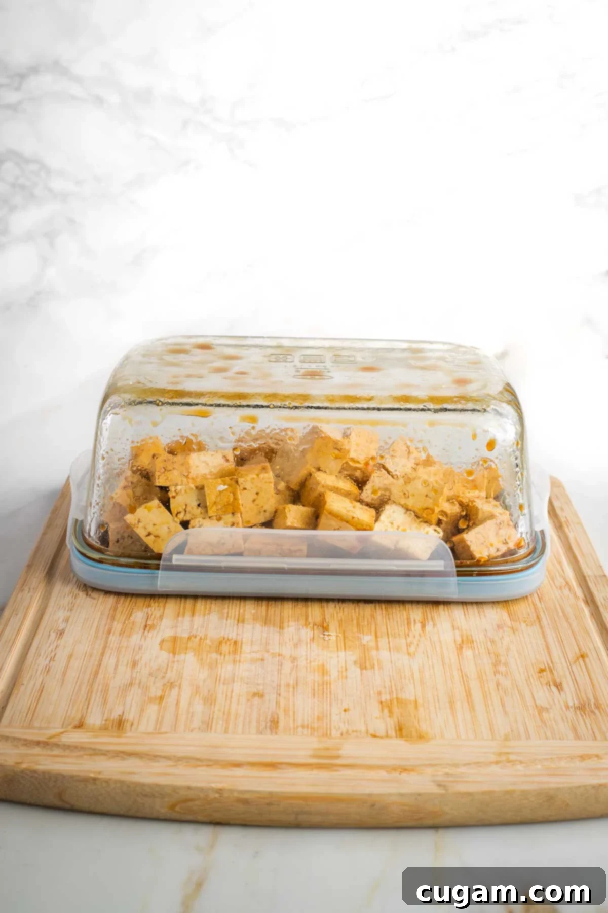 Glass dish turned upside down with cubes of marinating tofu.