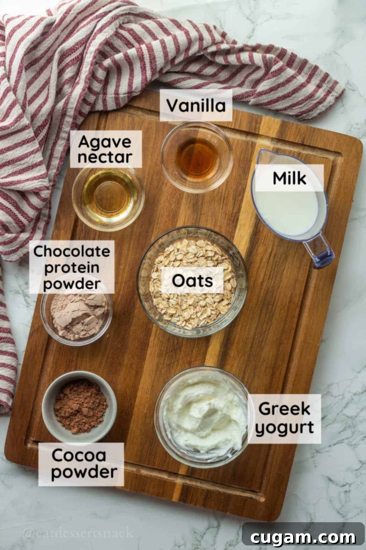 Ingredients for brownie batter overnight oats in glass bowls on wood cutting board with dish towel.