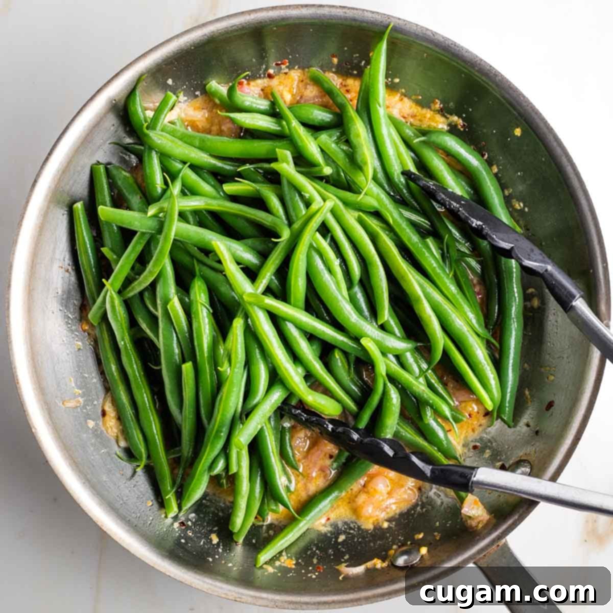 Skillet with lemony mustard sauce and a pile of green beans on top. 