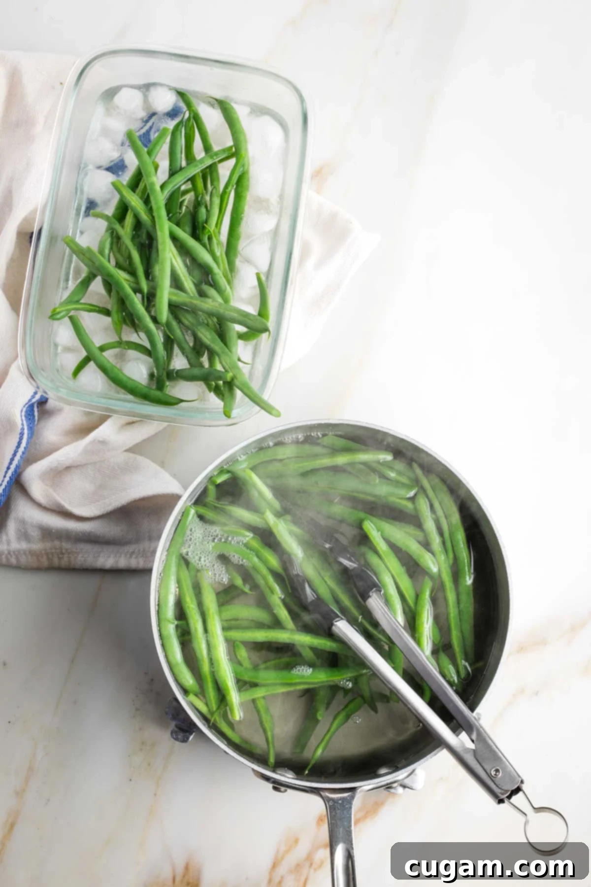 Tongs transferring green beans from cooking pot to container with ice water.
