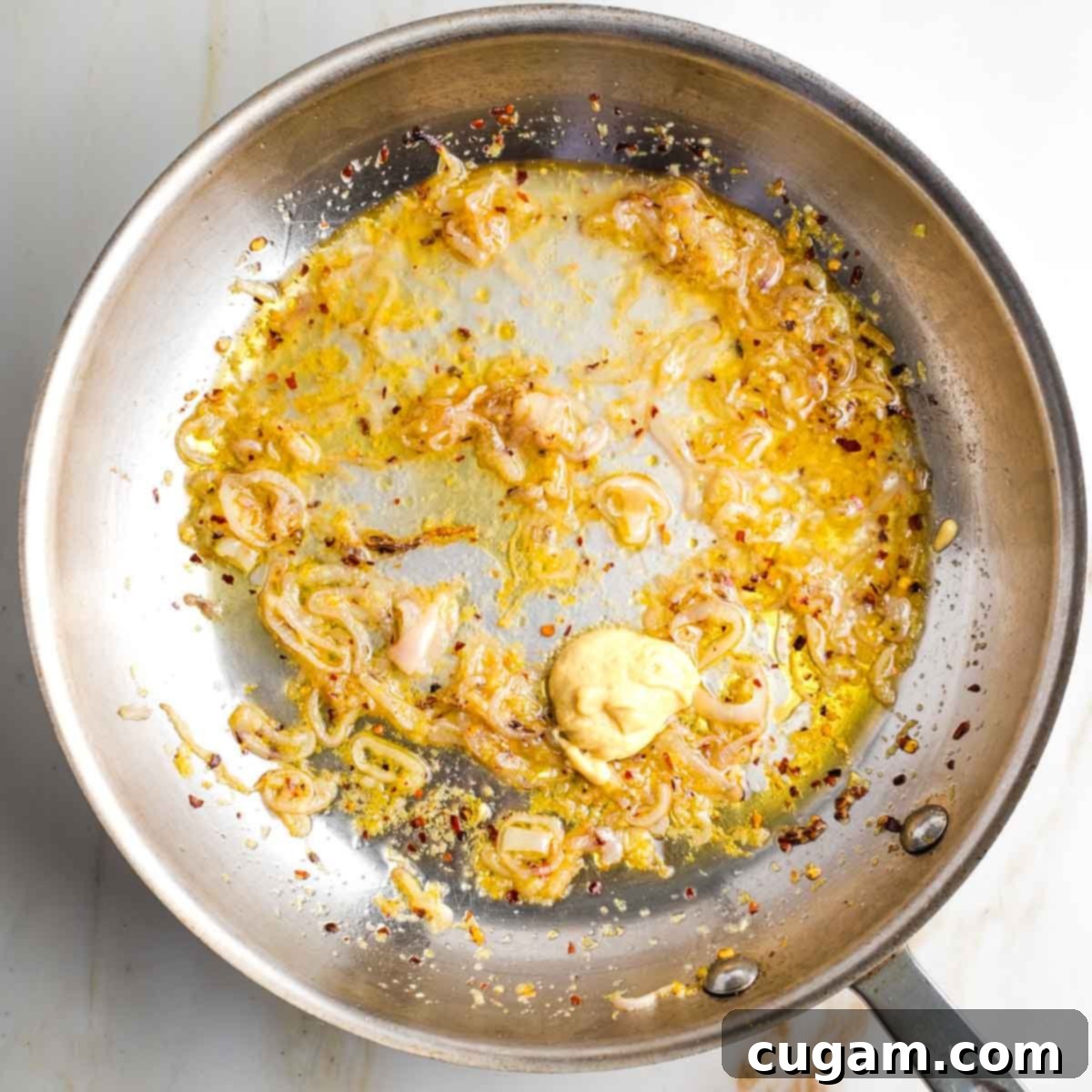 Fry pan with sauteed onions, mustard and garlic.