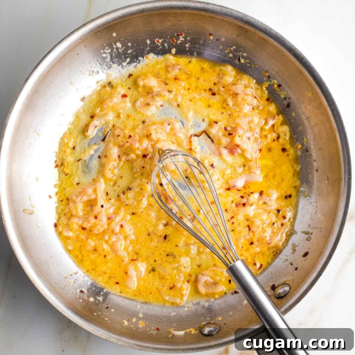 Whisking lemony sauce with shallots and mustard in a skillet.
