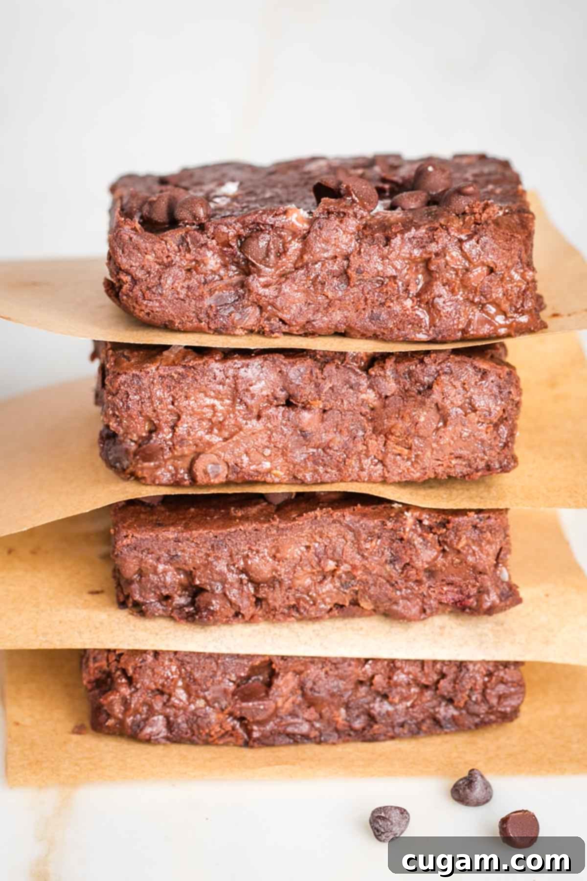 Fudgy view of a stack of brownies with parchment in between layers.