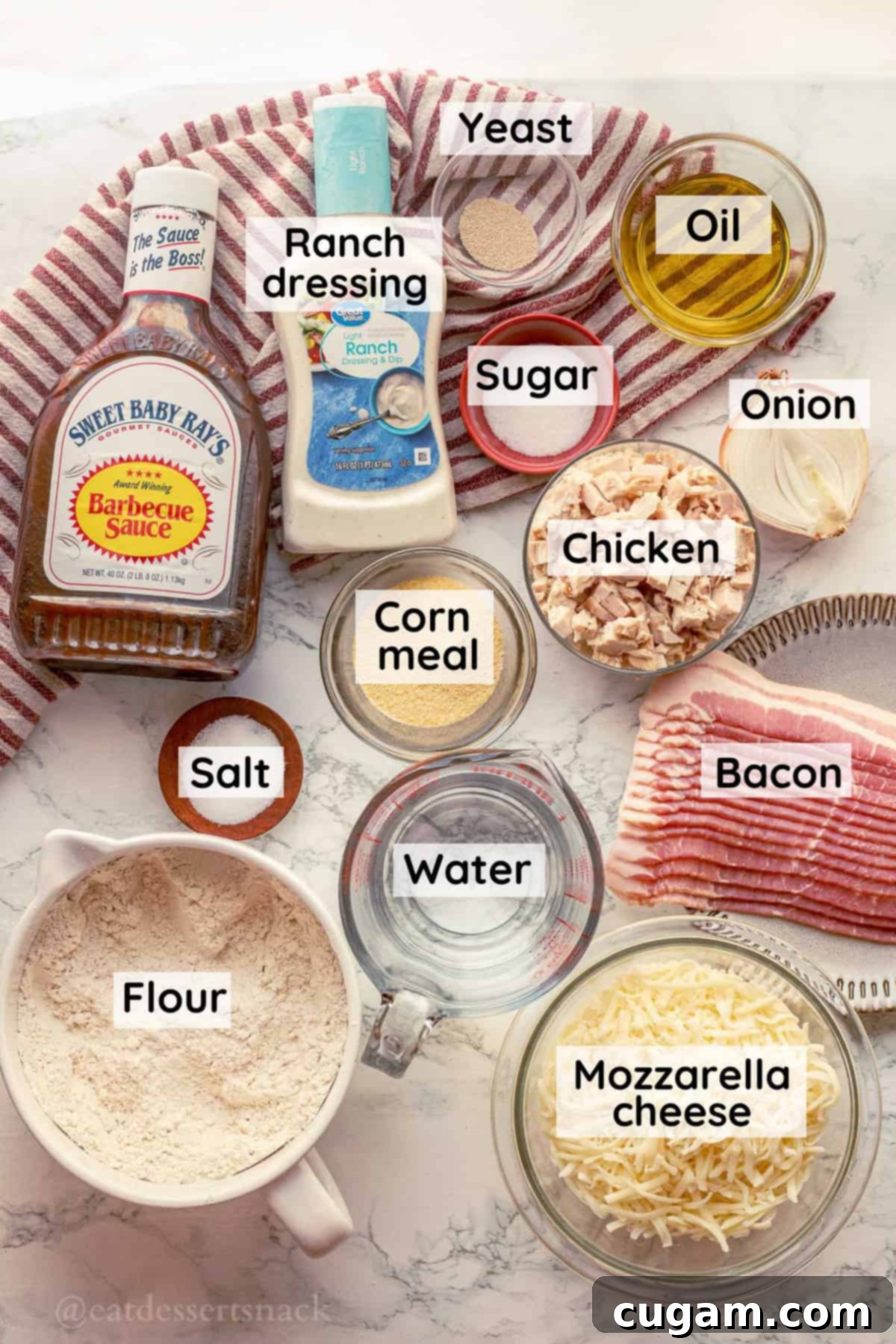 Arrangement of ingredients for BBQ chicken pizza in clear glass dishes on a pristine marble countertop, ready for preparation.