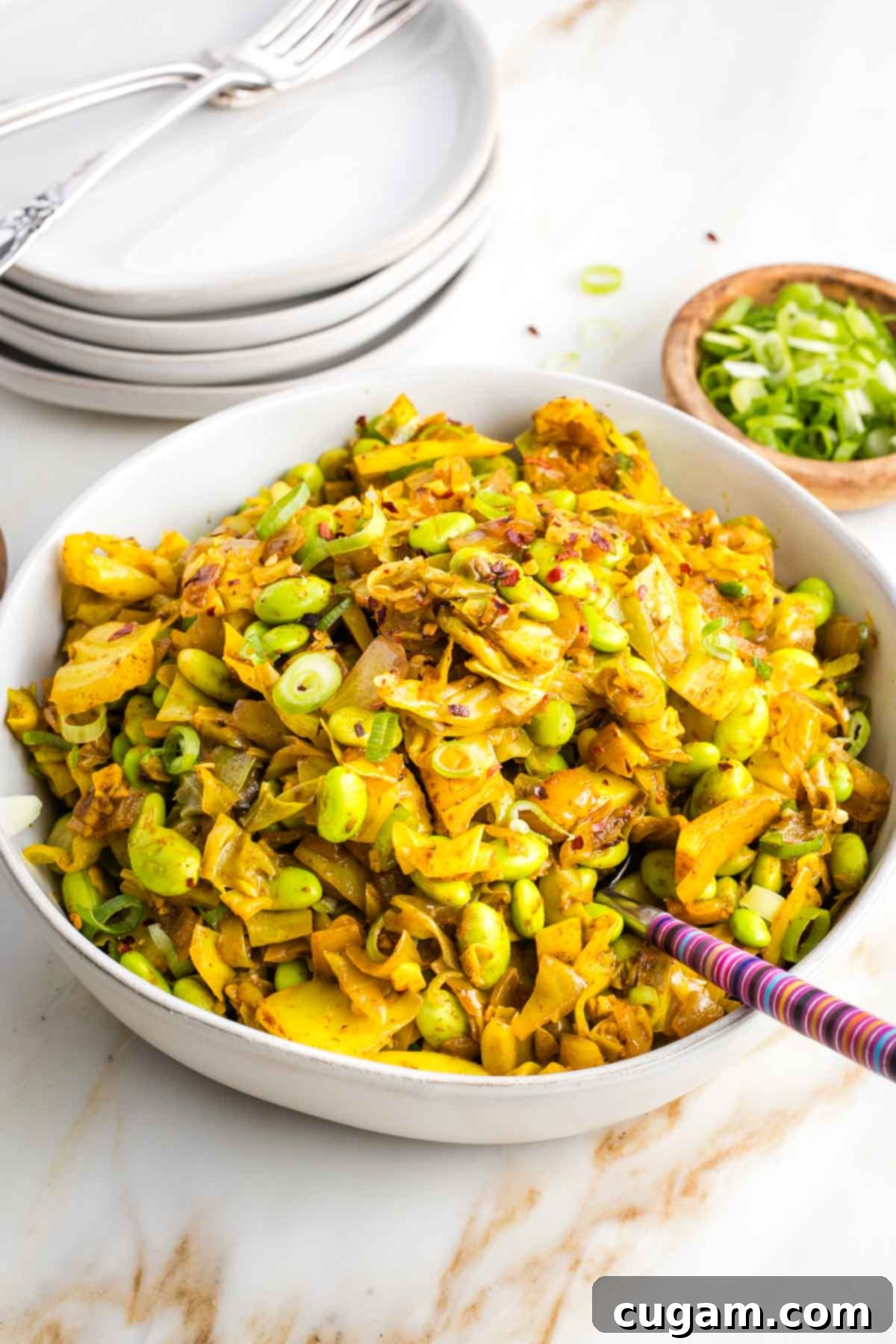 Chopped cabbage curry with edamame in a bowl, garnished with fresh herbs.