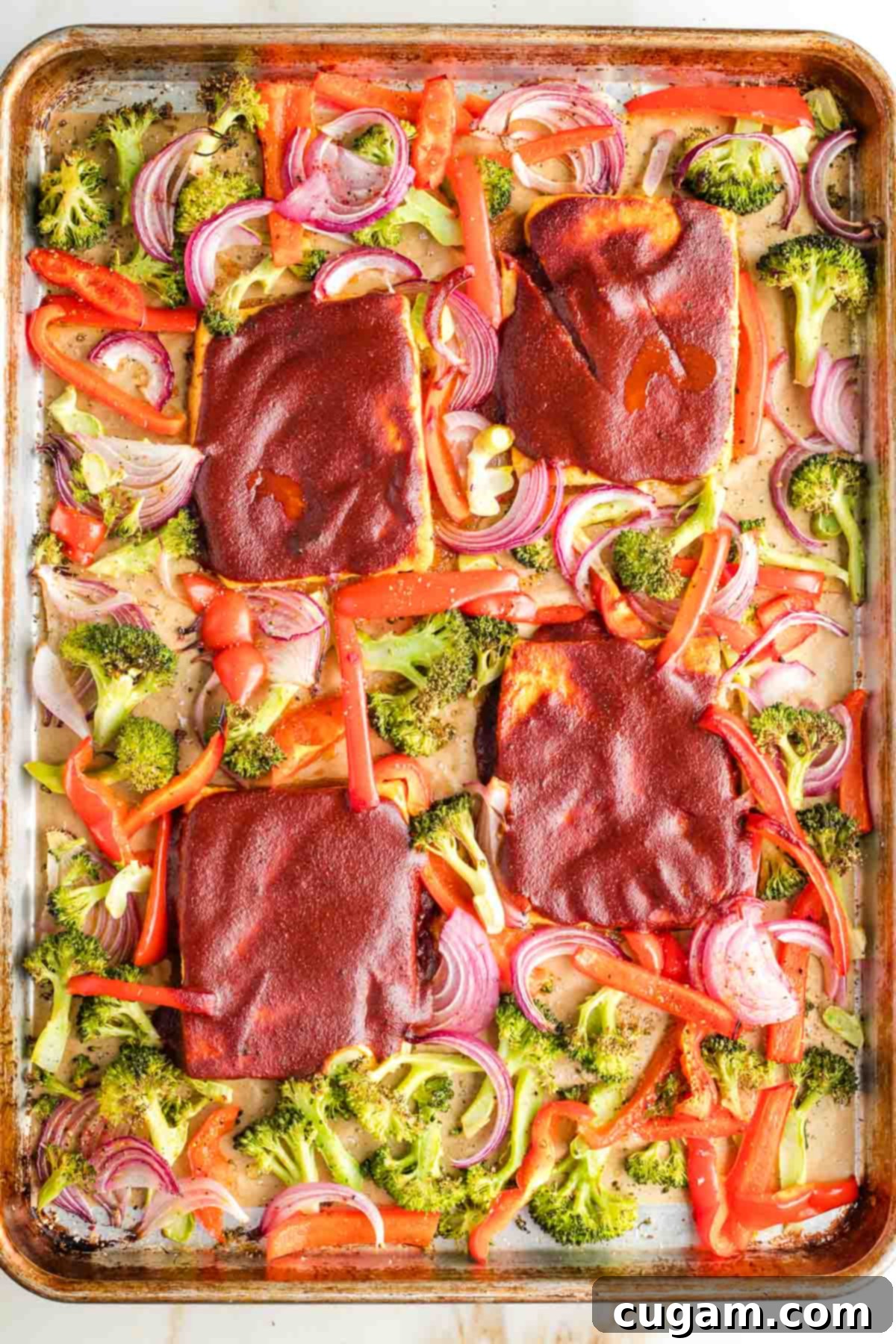 Tofu steaks with bbq sauce on a sheet pan with roasted broccoli, red peppers and onions.