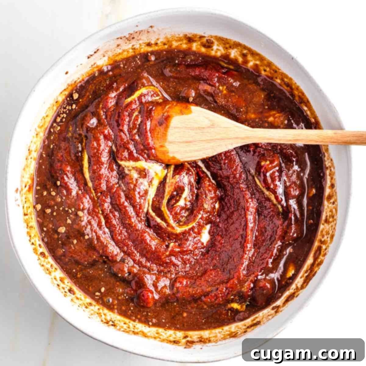 Thick, dark reddish/brown paste mixture in a bowl with yellow flecks.