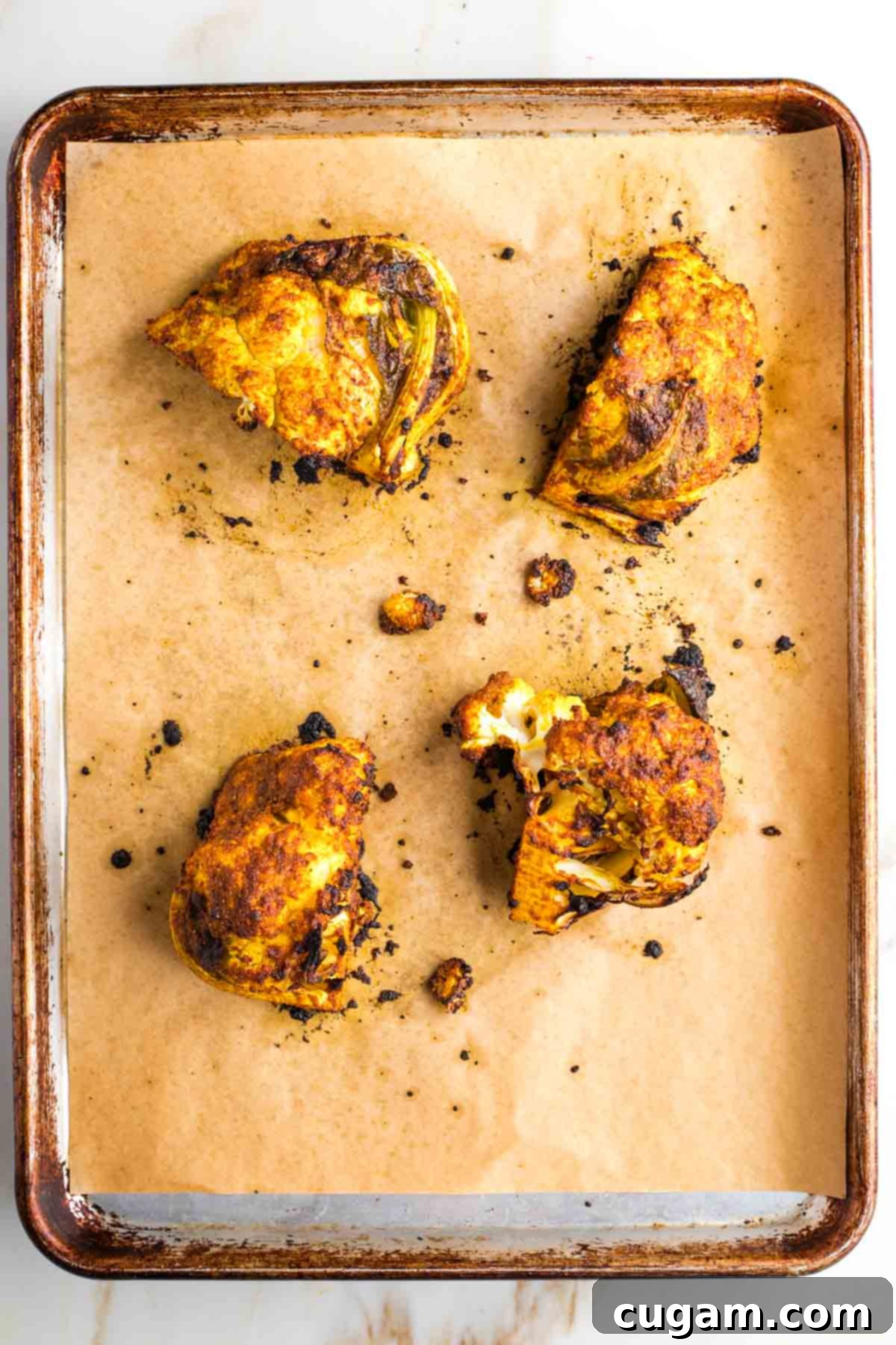 Roasted cauliflower  with shawarma paste on a baking sheet.