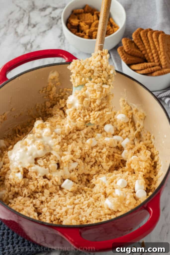 A large bowl containing a mixture of puffed rice cereal, melted marshmallows, and butter, ready for the next steps.