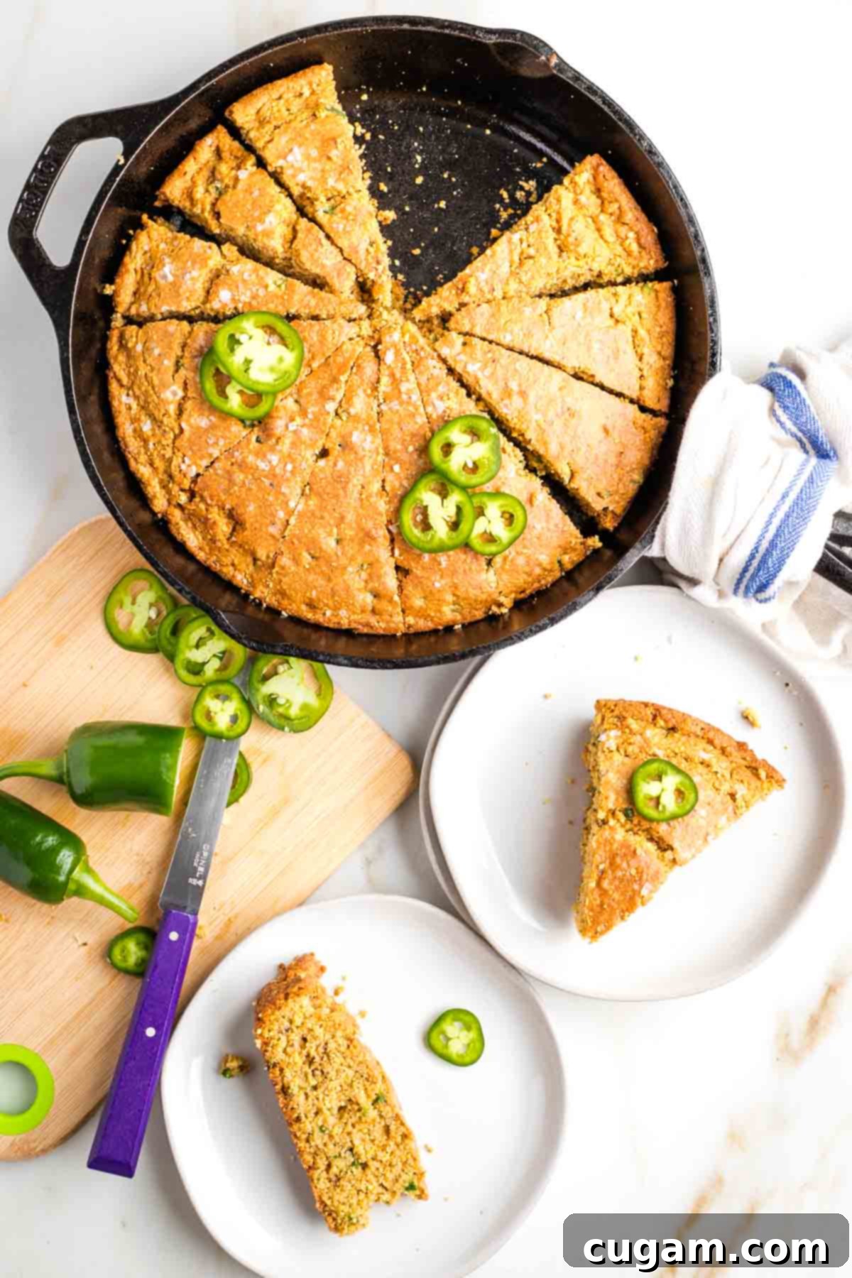 Skillet cornbread cut into pie slices with jalapenos on top and on the plated pieces. 