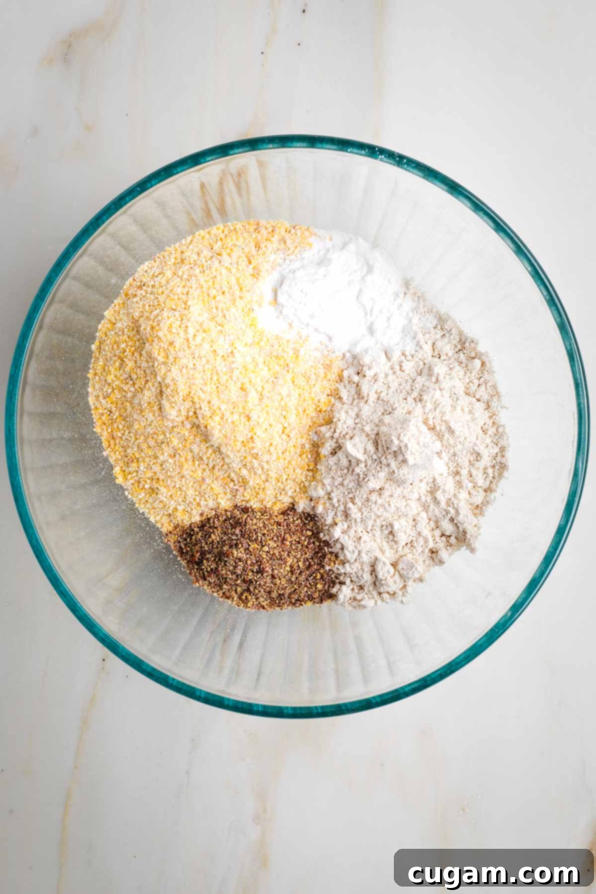 Cornmeal, flour, ground flax, baking soda and baking powder in a glass mixing bowl.