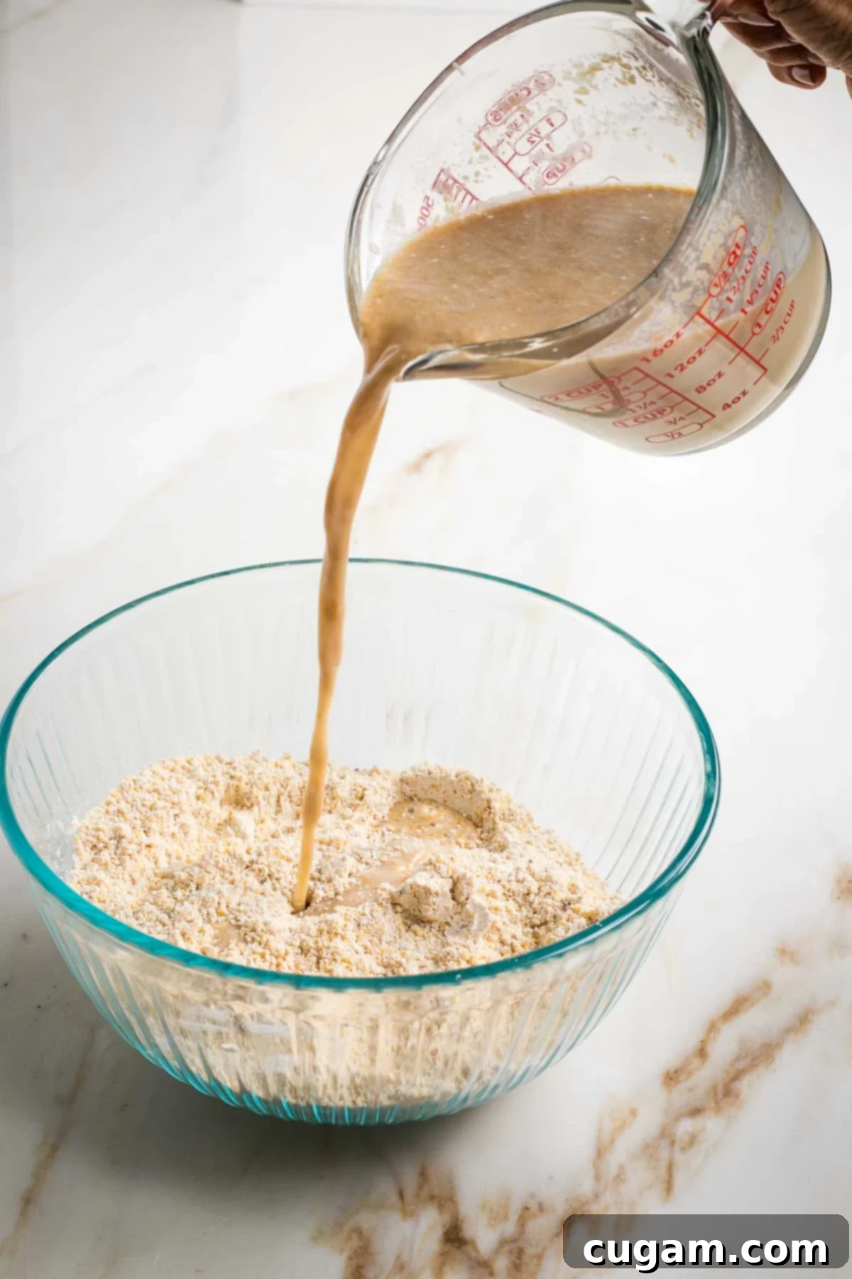 Pouring wet ingredients into dry to mix up cornbread batter.