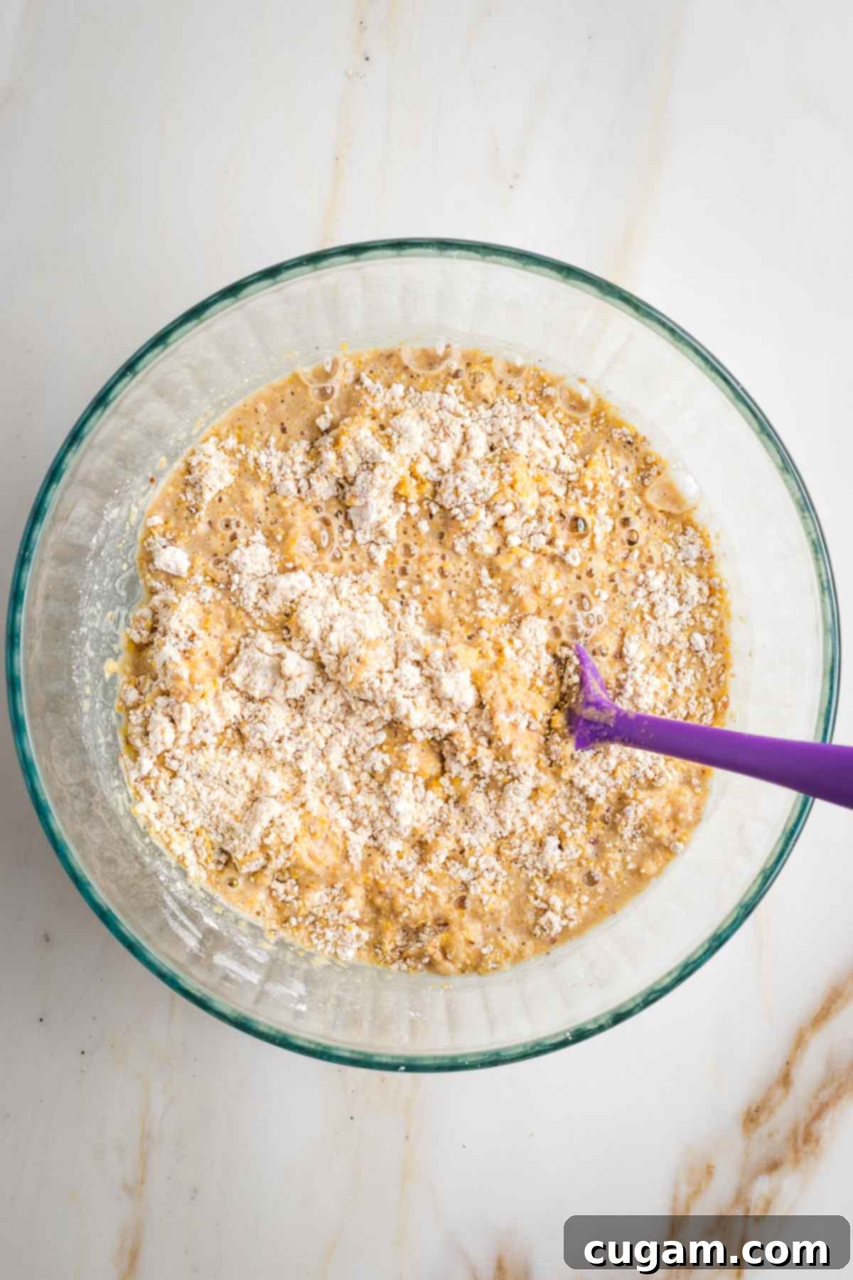 Stirring cornbread batter together, mixing the wet ingredients with the dry.