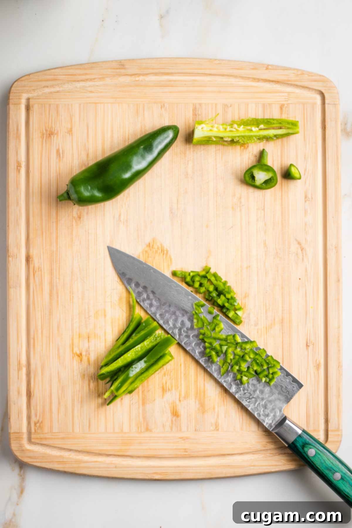 Showing how to dice a jalapeno by removing seeds and membranes, then cutting long strips and finally cutting across.