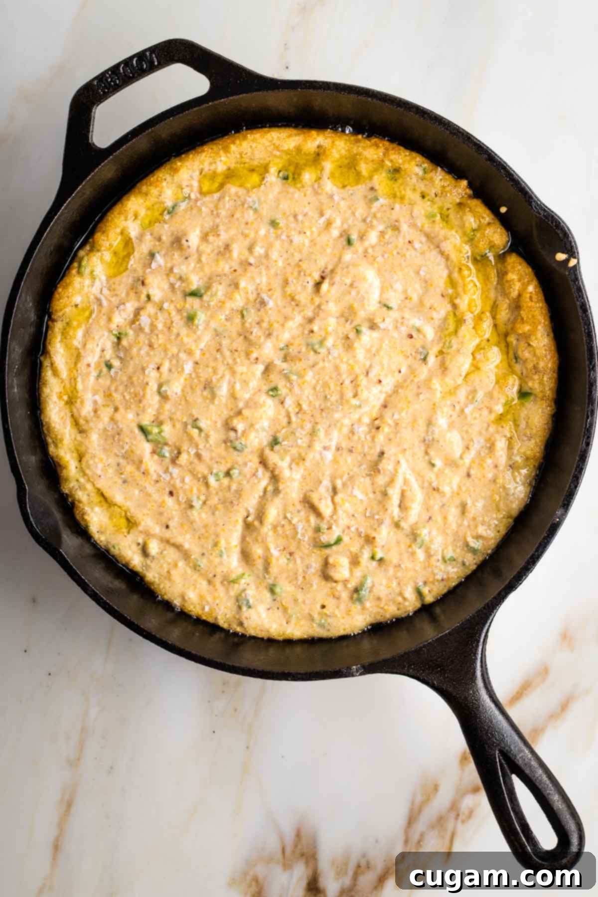 Cast iron skillet filled with cornbread batter.