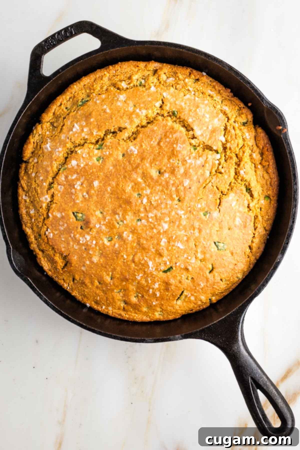 Golden brown skillet cornbread with a crack through the top straight across.