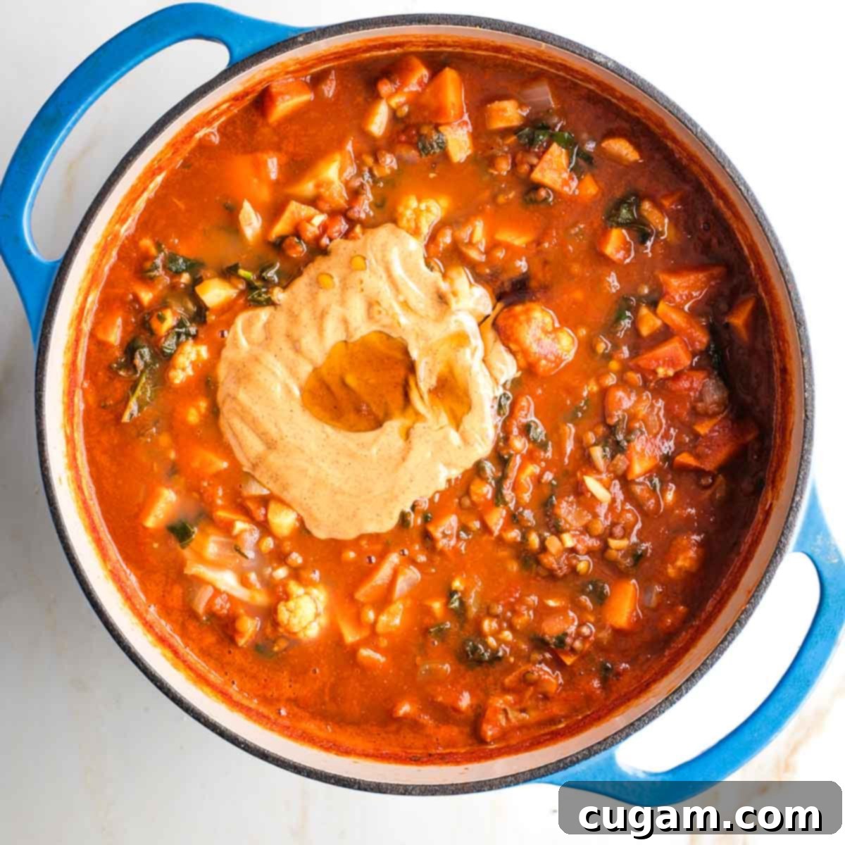 Peanut butter and maple syrup on top of a pot of tomato based veggie stew.