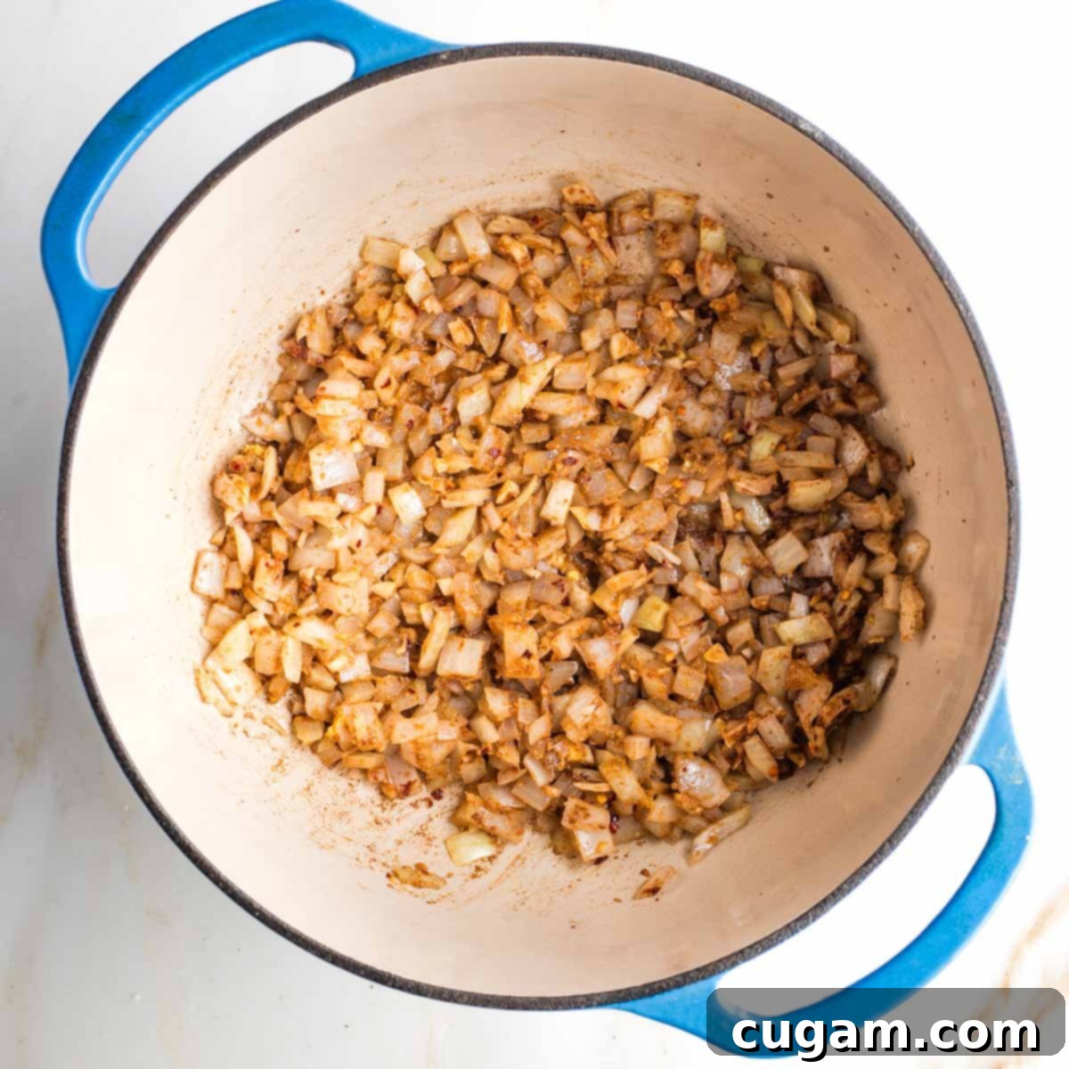 Spices coating onions, ginger and garlic inside a dutch oven.
