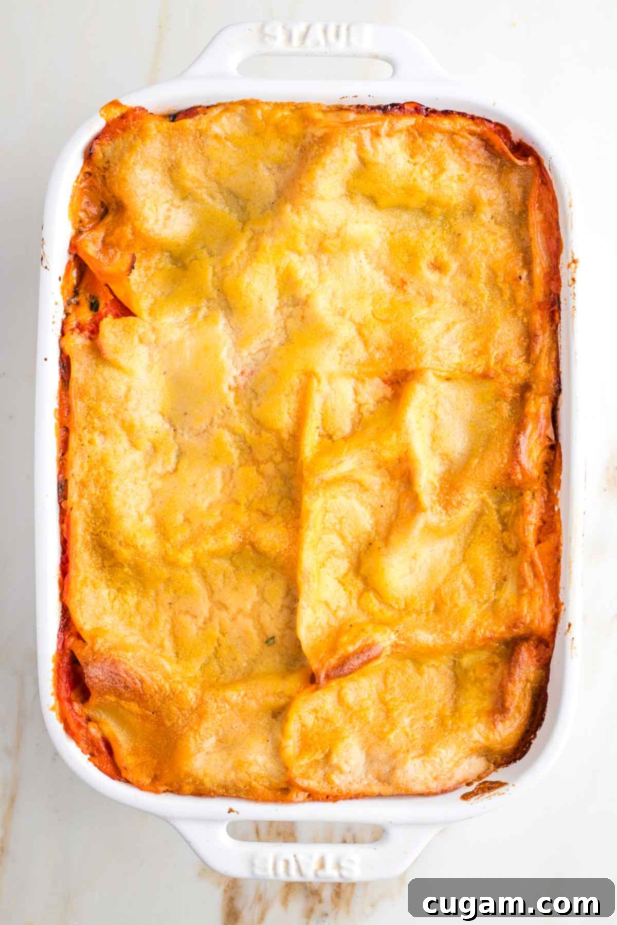 Baked lasagna in a baking dish, sauce bubbling around the edges. 