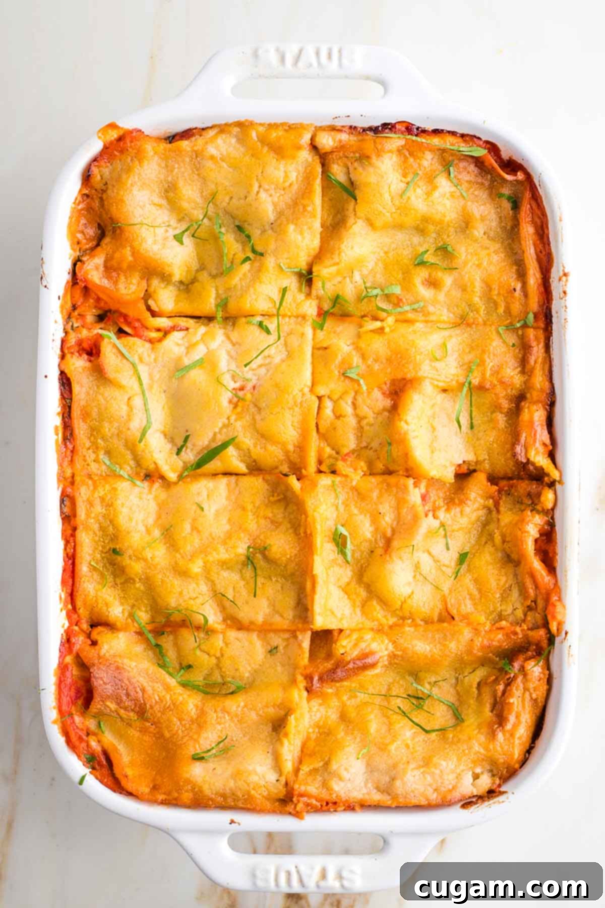 Baked lasagna, cut into 8 pieces and sprinkled with fresh herbs.