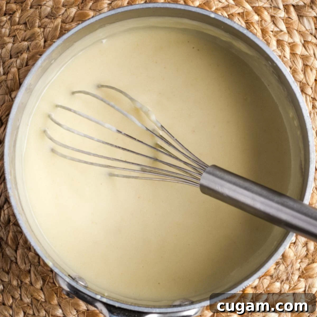 Small saucepan whisking together bechamel sauce.
