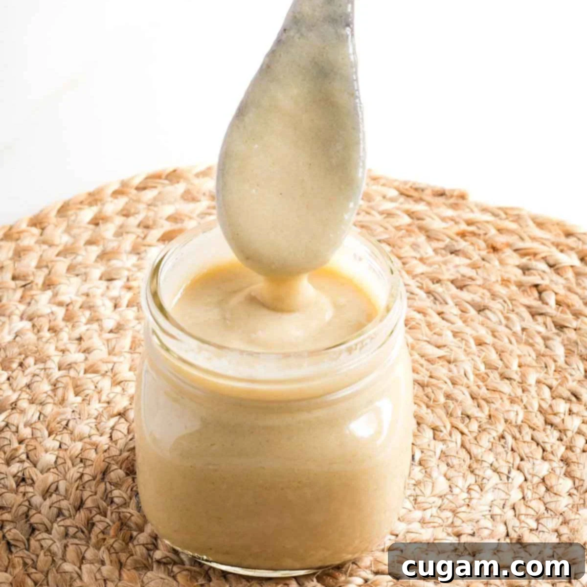 Wooden spoon coming out of a jar of bechamel sauce, showing how thick it is.