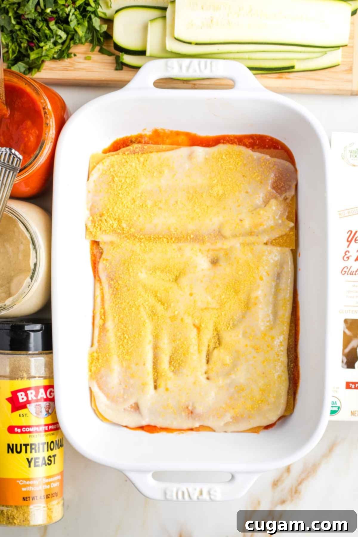 Baking dish layered with red sauce, noodles, bechamel and nutritional yeast.