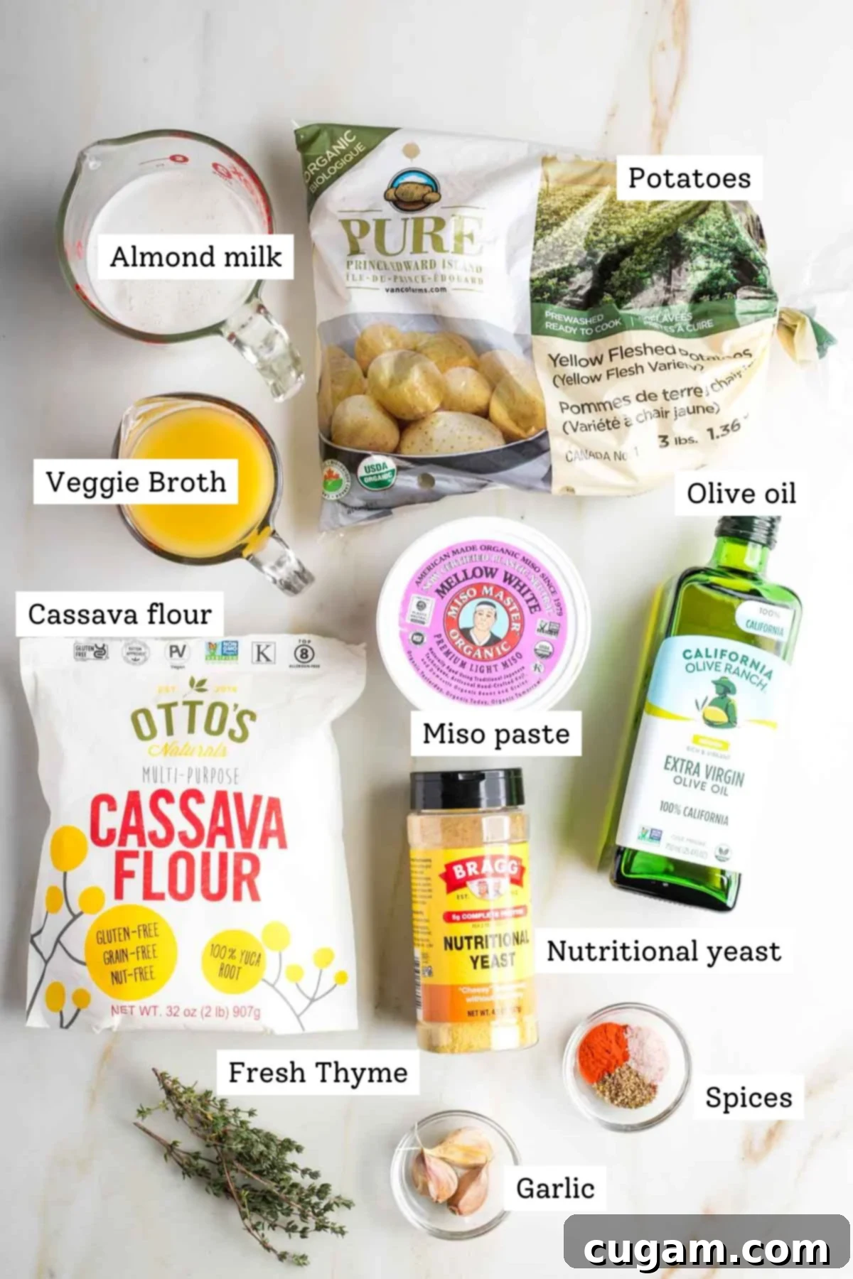 Labeled ingredients for dairy-free scalloped potatoes recipe. Miso, broth, plant milk, olive oil, cassava flour, fresh herbs, garlic and spices.