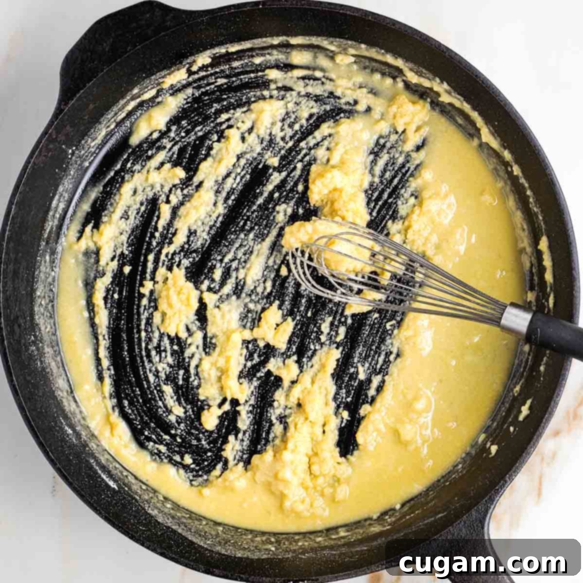 Whisking a roux together in a cast iron skillet.