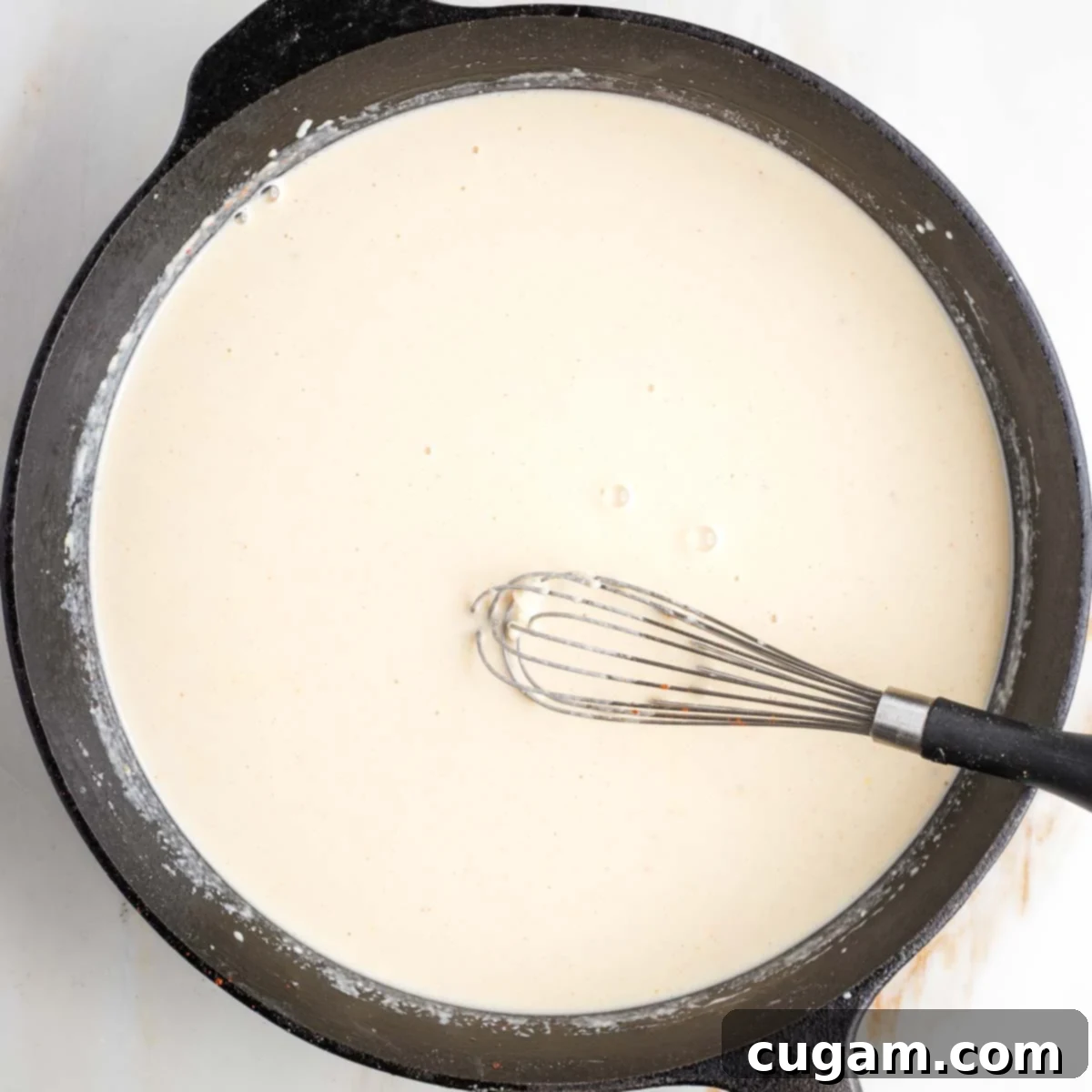 Smooth and creamy white sauce in a cast iron skillet.