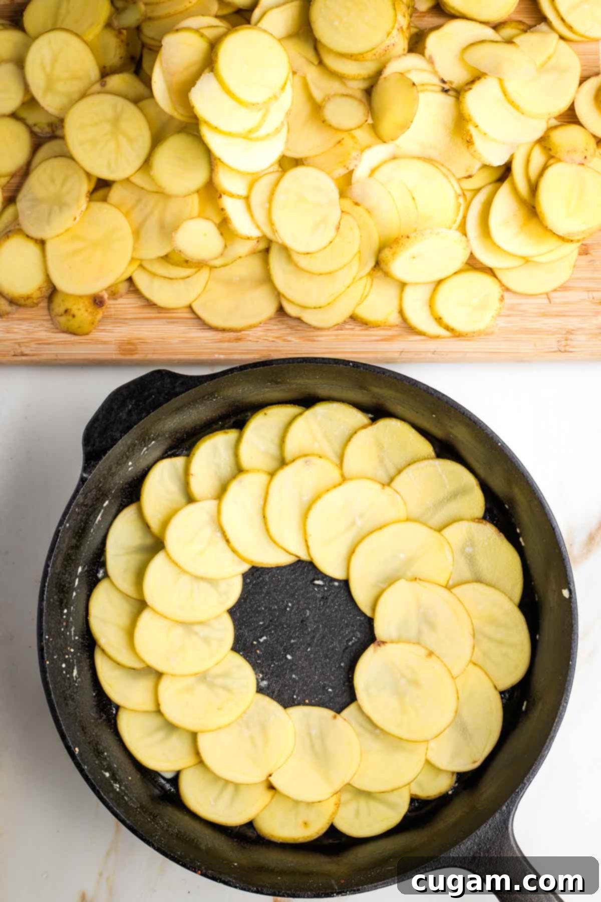 Two rings of thinly sliced potatoes placed into a cast iron skillet.
