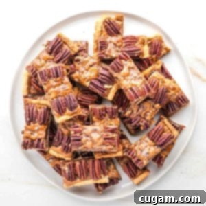 Plate piled with pecan pie bars, with a pie crust, caramel layer and pecan halves decorating the top.