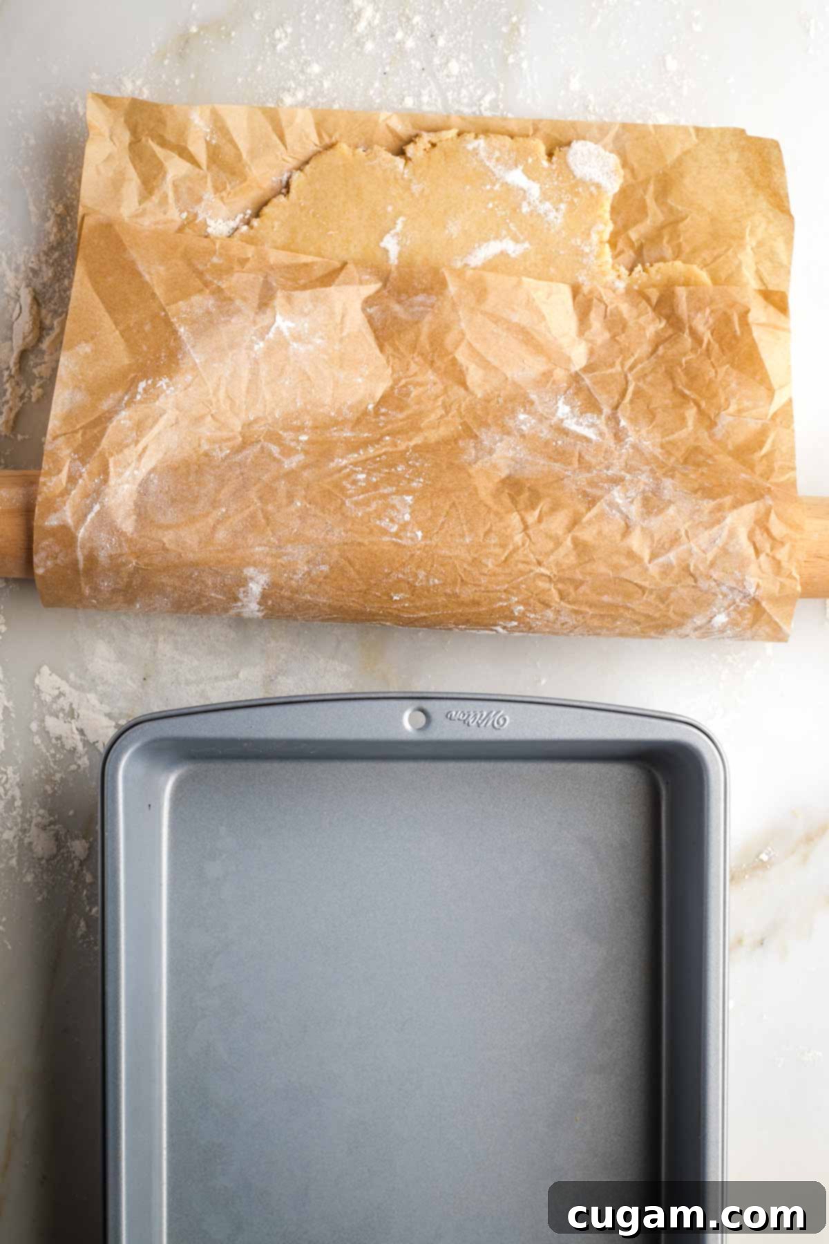 Pie crust on parchment paper, spread over rolling pin to help transfer it to baking dish. 