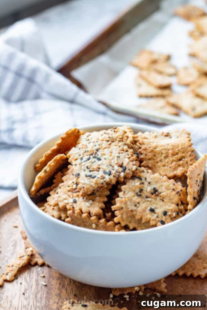 Perfectly baked sourdough discard crackers with garlic and parmesan, arranged in a white bowl on a rustic wooden board, ready for serving.