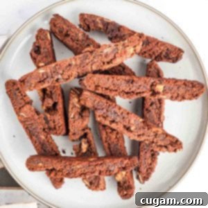 A plate full of crunchy chocolate biscotti studded with chocolate chips and almond slivers, ready to be enjoyed.