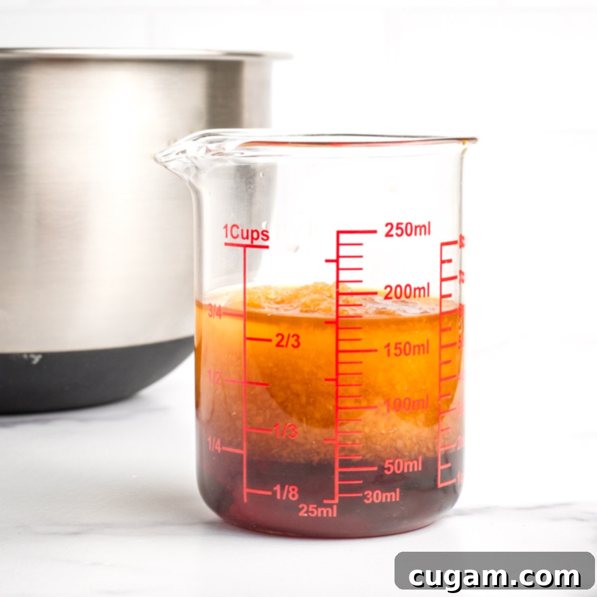 A glass measuring cup holding the mixed wet ingredients, with a mixing bowl in the background, ready for combination.
