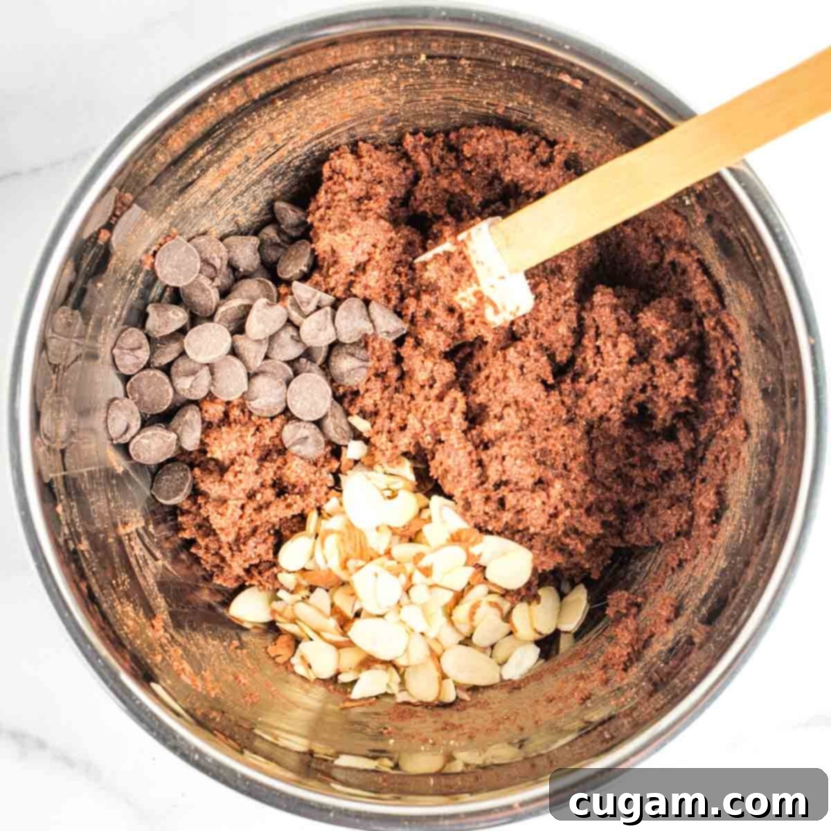 Irresistible Vegan Gluten-Free Chocolate Almond Biscotti 8 Chocolate biscotti batter, with a pile of chocolate chips and sliced almonds waiting to be mixed in.
