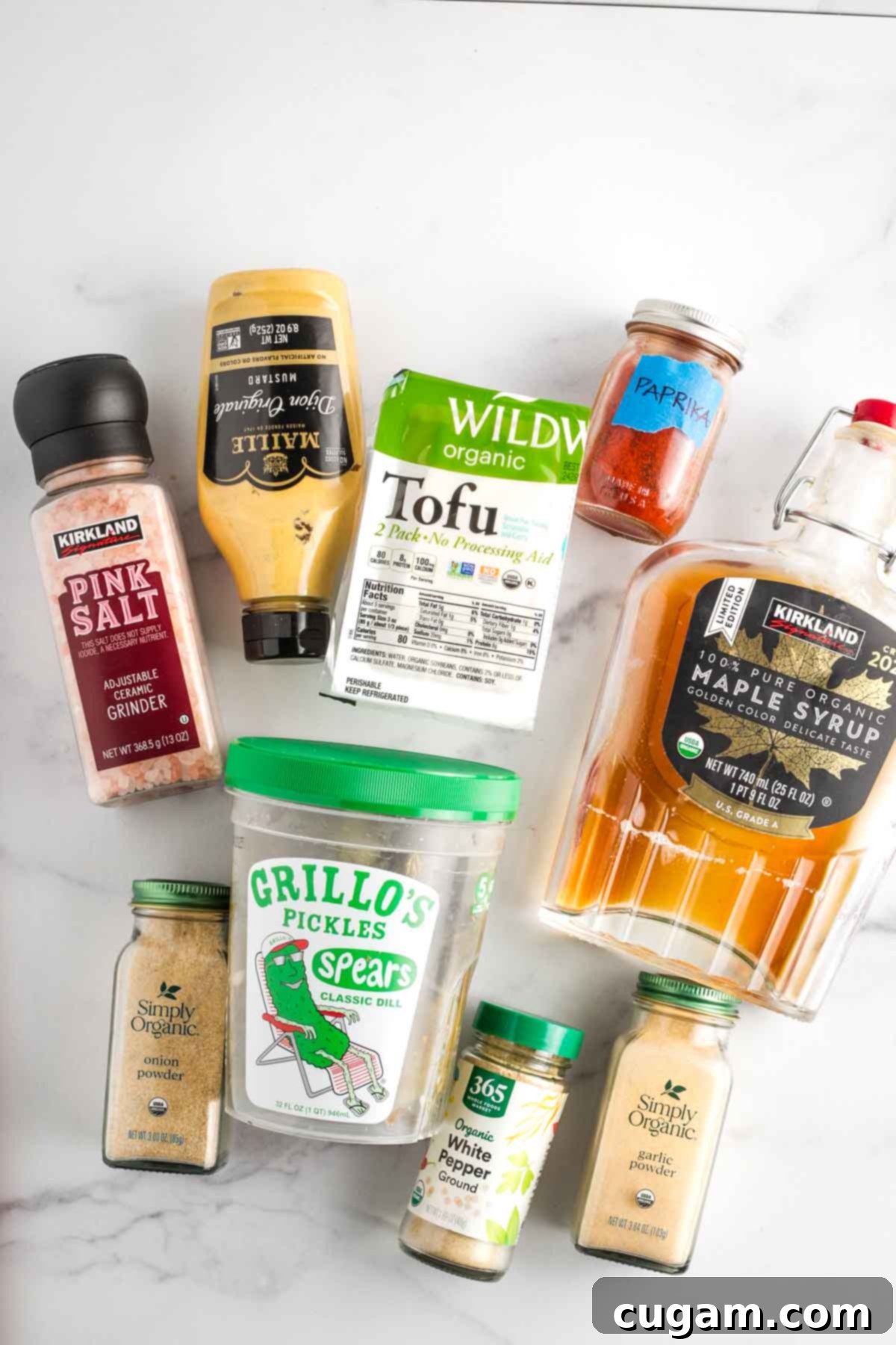 A collection of ingredients for the vegan burger sauce: tofu, pickle juice, maple syrup, and various spices arranged on a counter.