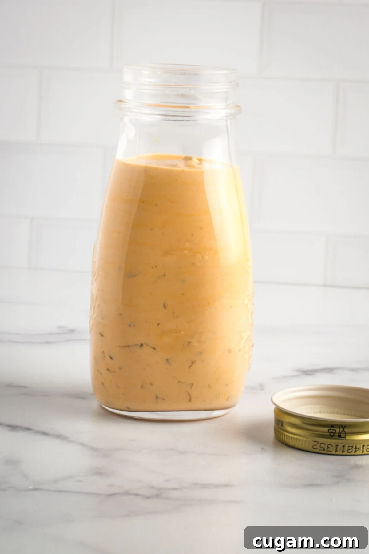 Small jar of peach-colored burger sauce with visible diced pickles floating within.