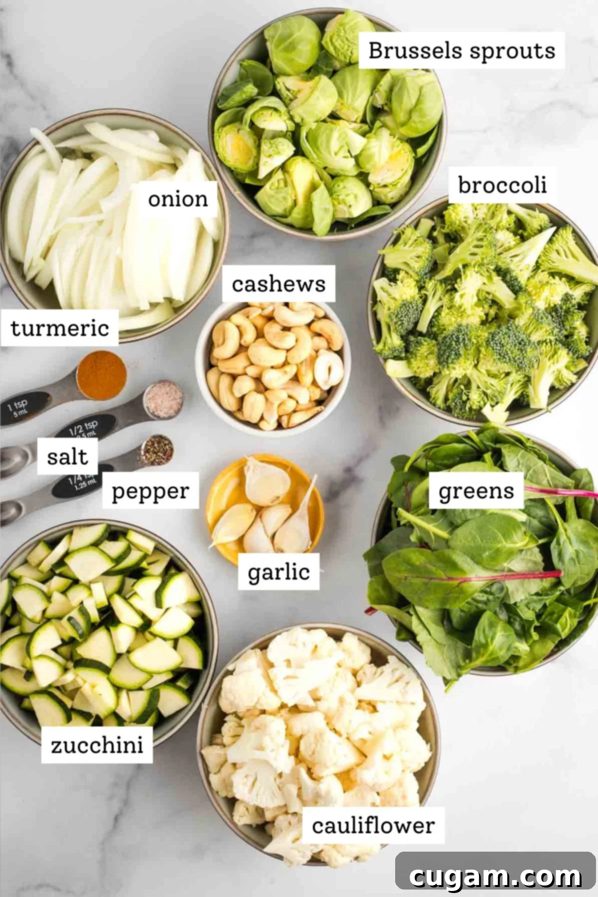 Labeled ingredient shot for green blender soup: chopped veggies, spices, cashews, garlic and greens.