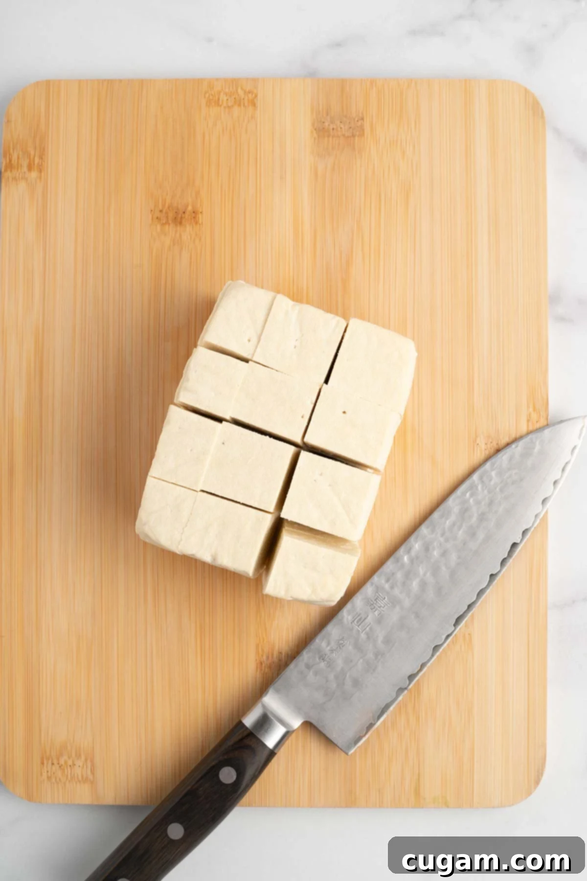 Sticky Sweet and Sour Crispy Tofu 14 Stacked tofu slices being cut into long strips, then crosswise into cubes.