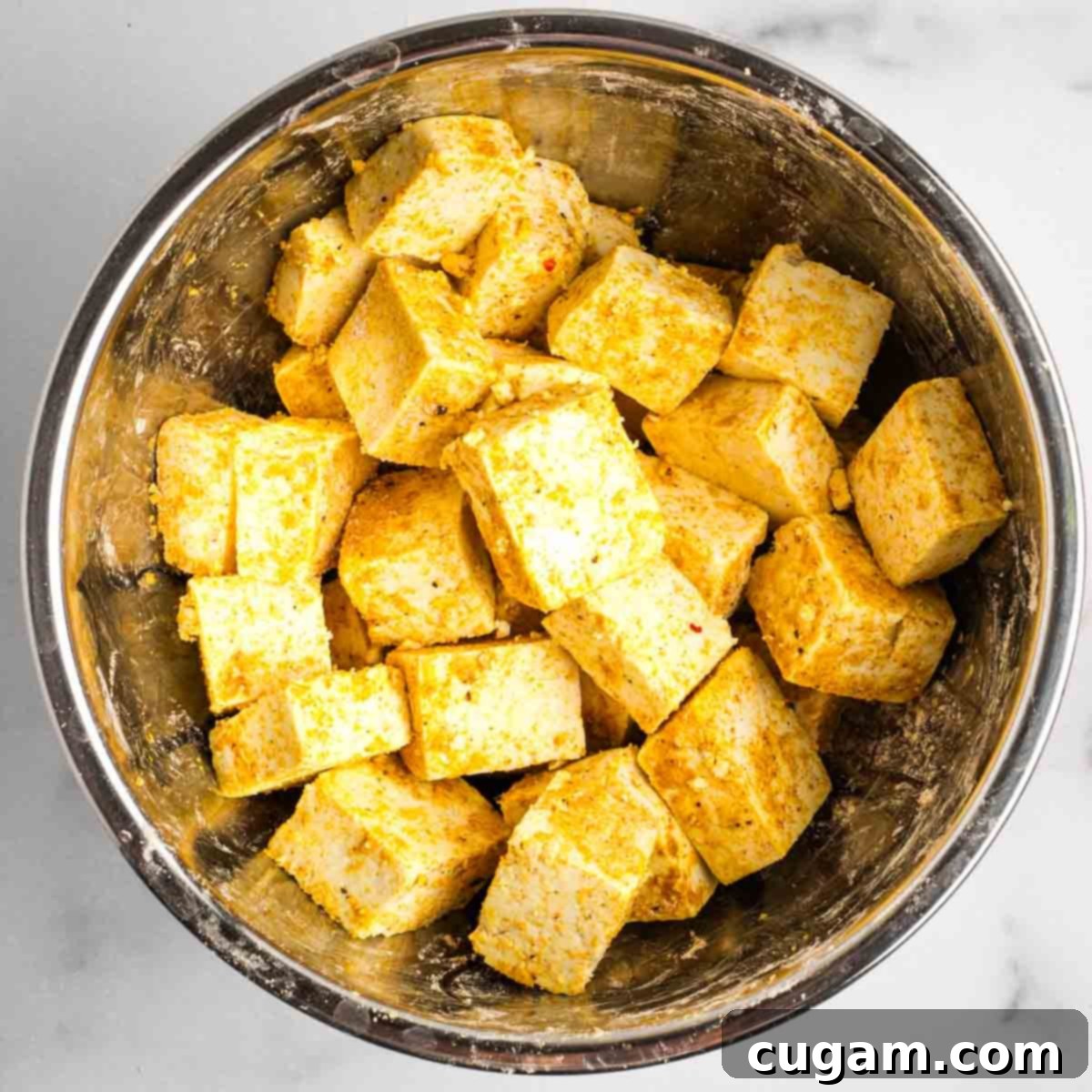 Sticky Sweet and Sour Crispy Tofu 16 Tofu cubes being gently tossed in the seasoning mixture until evenly coated.