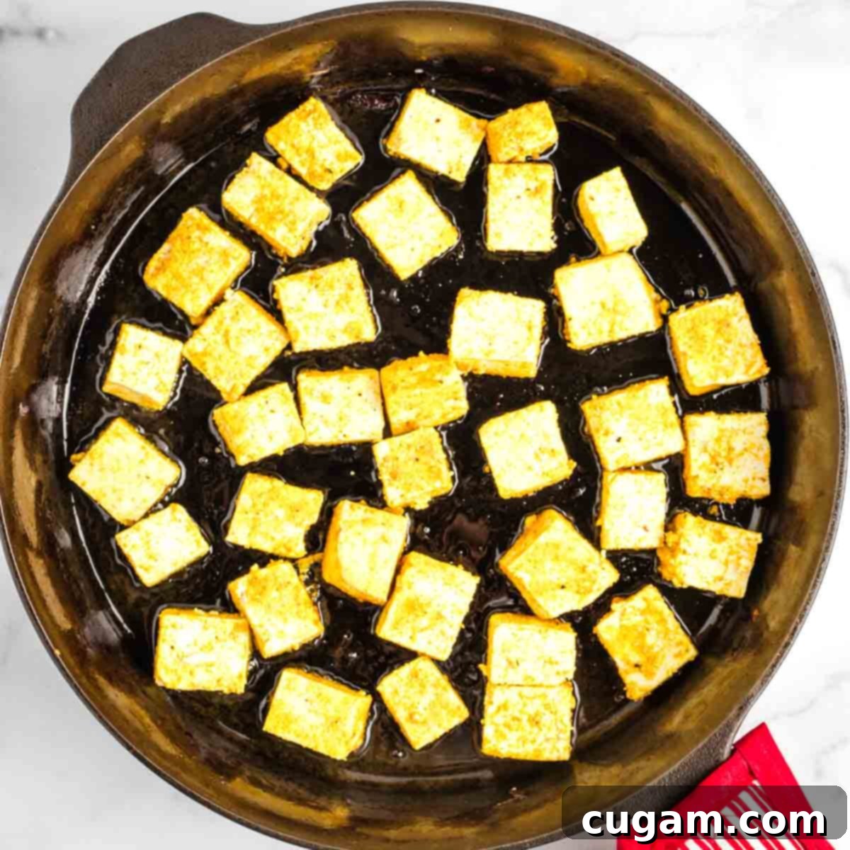 Sticky Sweet and Sour Crispy Tofu 17 Coated tofu cubes placed in a hot skillet with shimmering avocado oil.