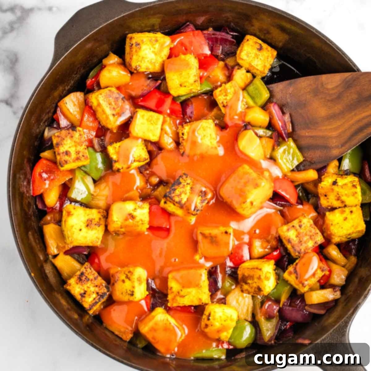 Sticky Sweet and Sour Crispy Tofu 20 Sweet and sour sauce being poured over the tofu and vegetables in the skillet.
