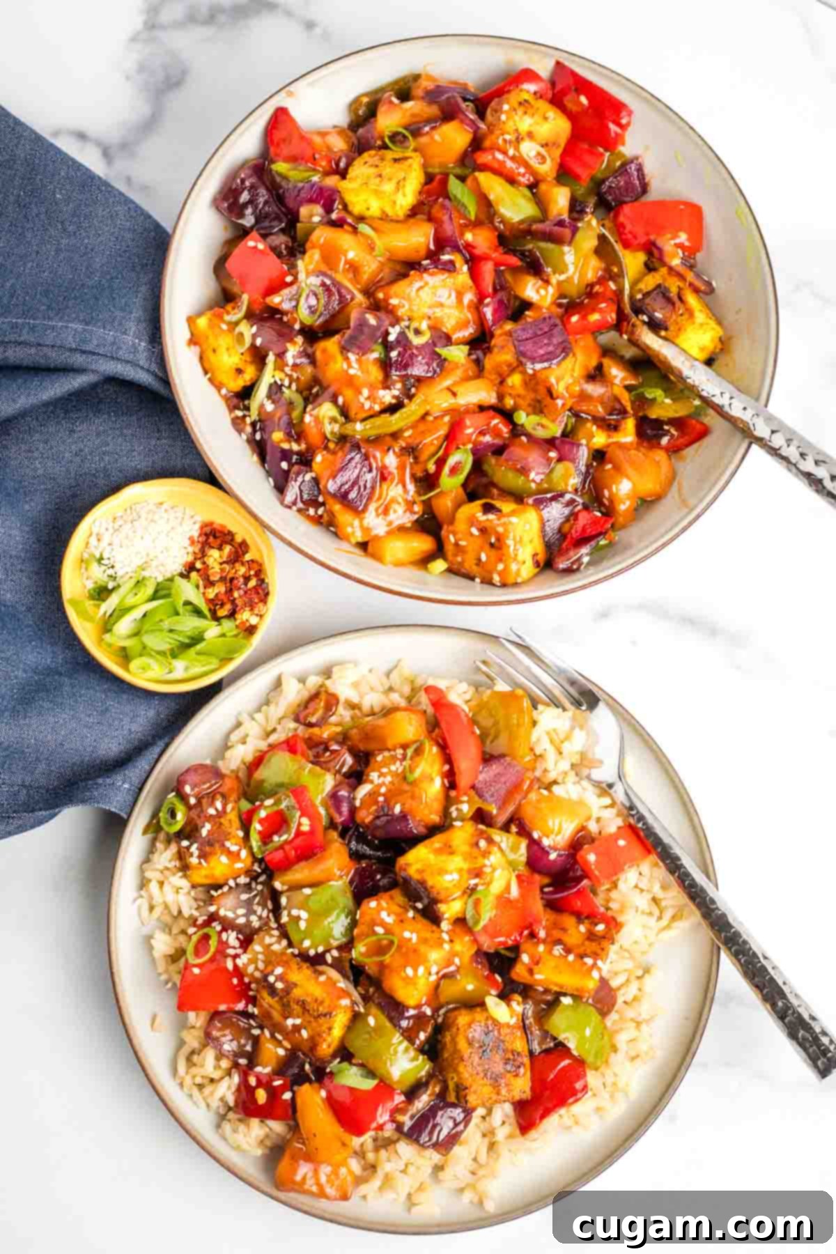 Sticky Sweet and Sour Crispy Tofu 22 Tofu and vegetables in a sweet and sour sauce, served over rice with chopsticks.