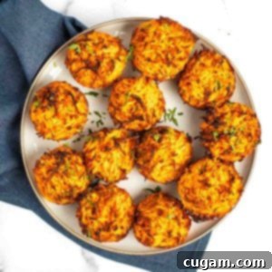 Individual sweet potato kugel cups on a plate, sprinkled with fresh herbs.