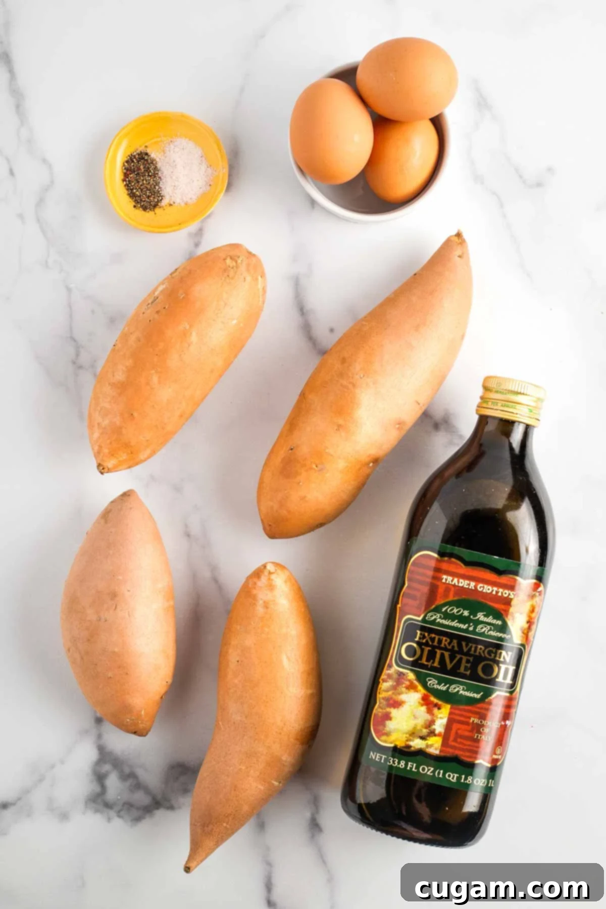 Sweet potatoes, brown eggs, bottle of olive oil, dish with salt and pepper. All ingredients are neatly arranged on a rustic wooden surface, highlighting their freshness and simplicity.