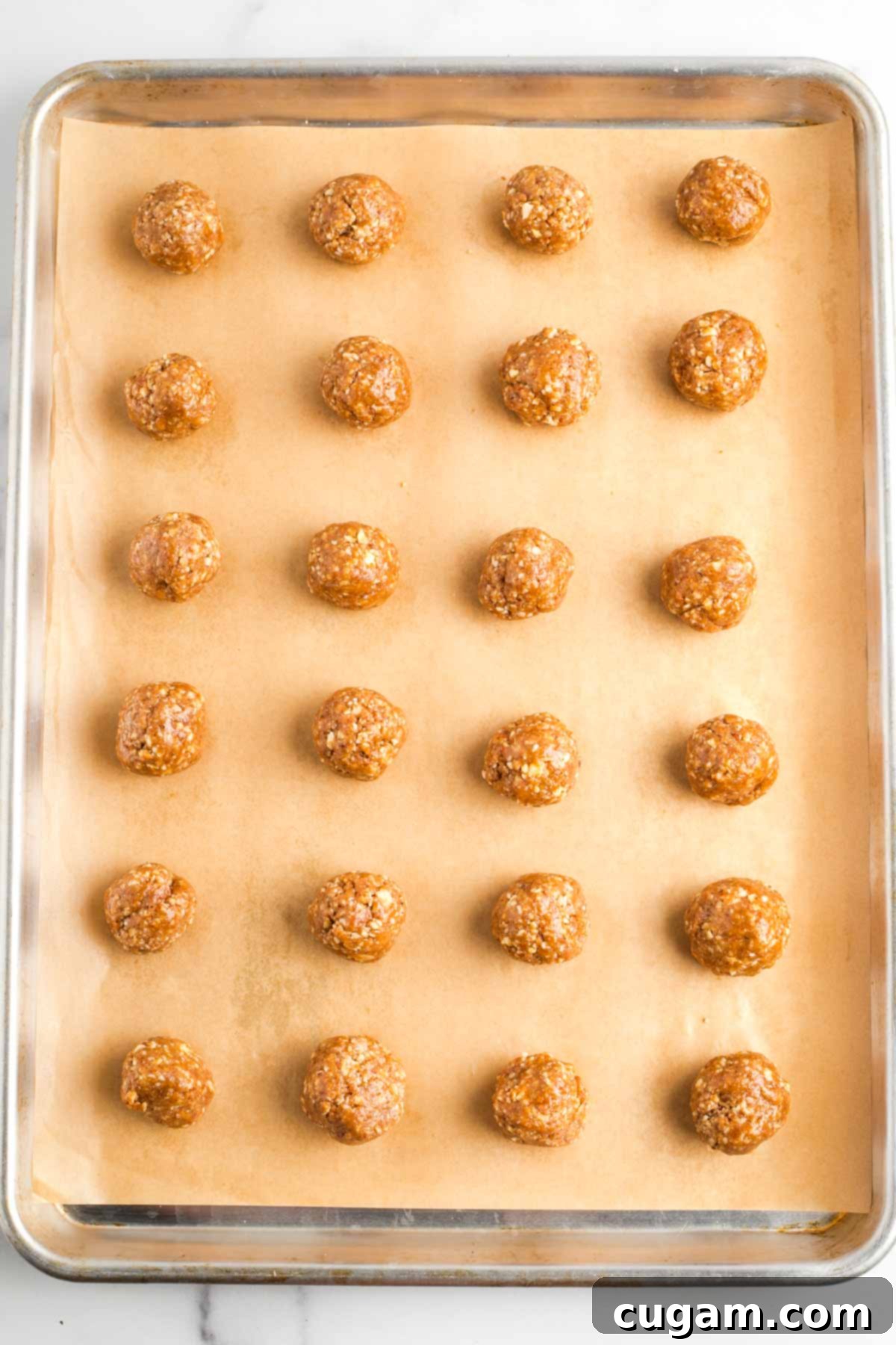 Decadent Vegan Almond Macaroons Enrobed in Chocolate 12 Almond cookies, rolled into balls, on a parchment lined baking tray.