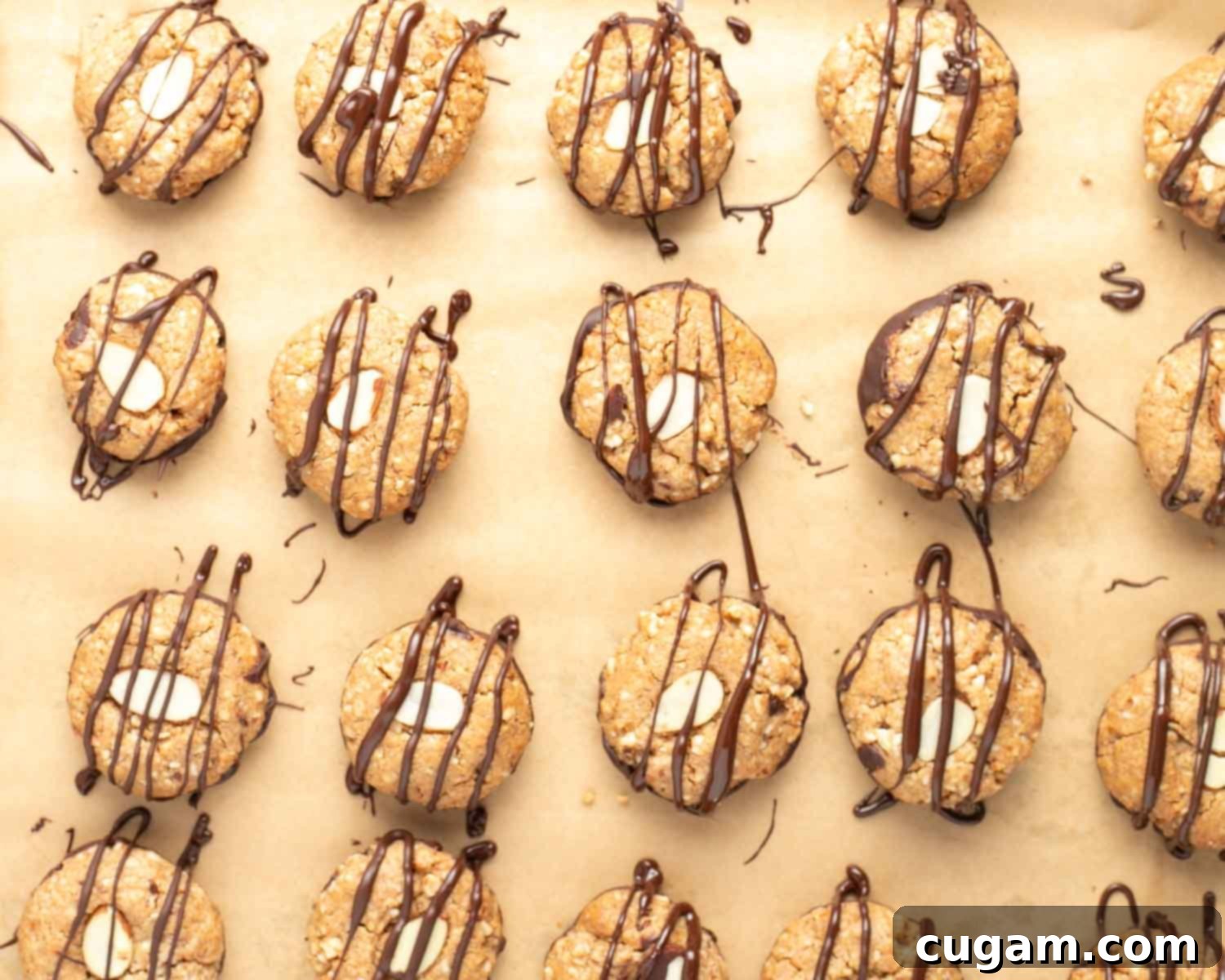 Almond macaroons flipped right side up, with a decorative chocolate drizzle being applied to the tops.