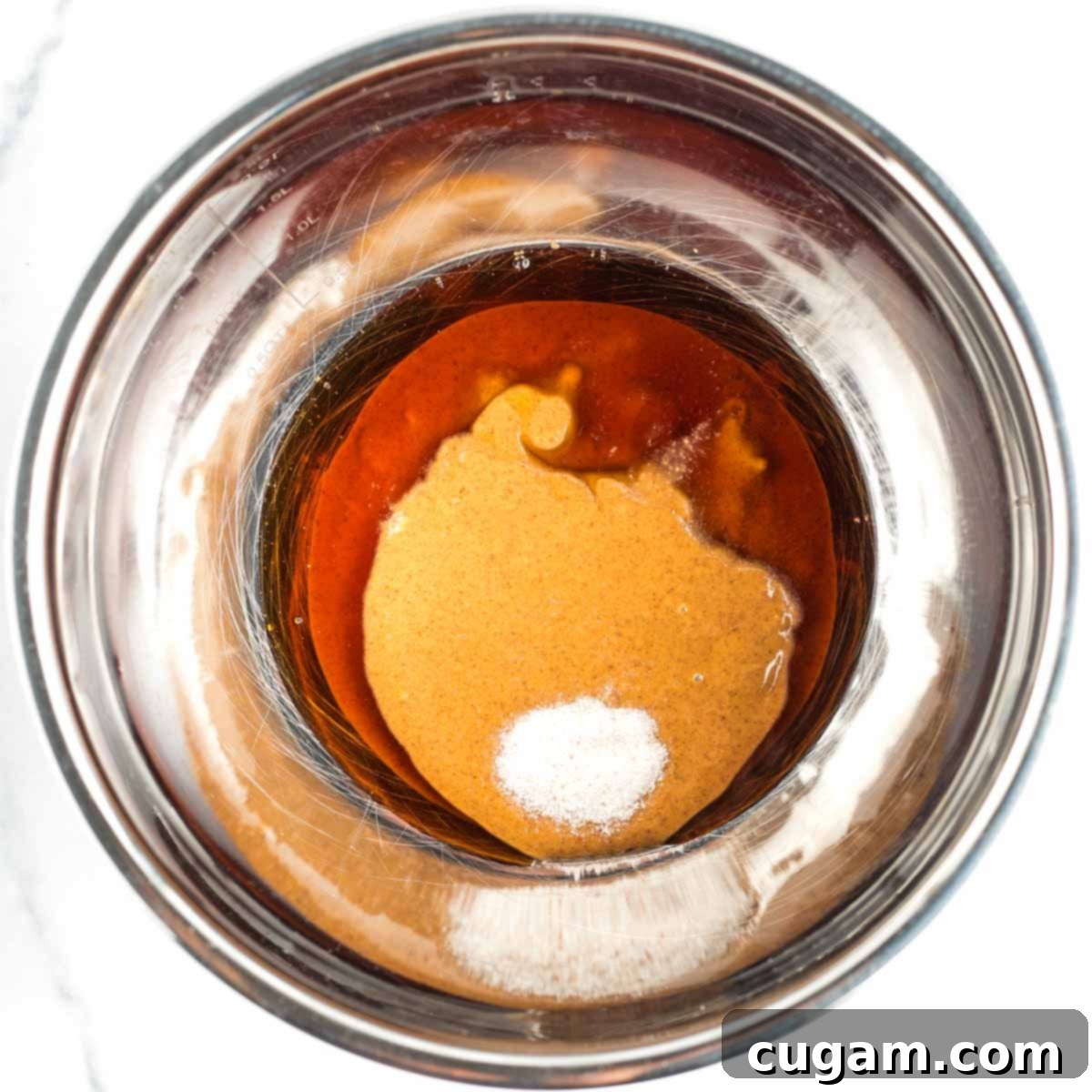 Mixing bowl with almond butter, maple syrup, and sea salt being combined.